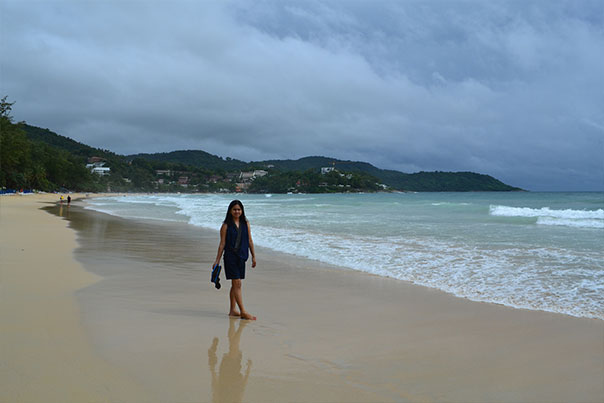 A woman walking barefoot at Kata Beach, Phuket
